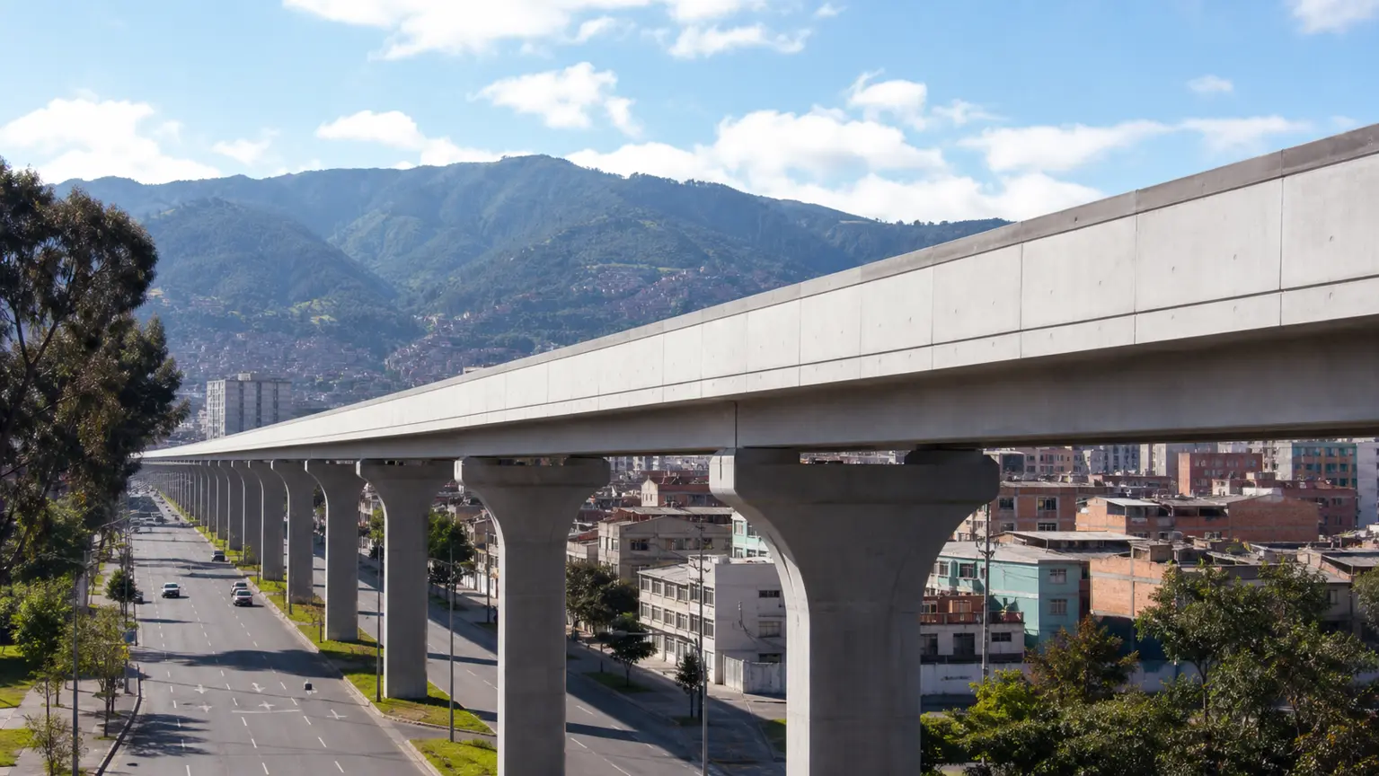 Viaducto elevado de la Línea 1 del Metro de Bogotá ya construido, visto desde una avenida de Bogotá, con la ciudad y los cerros orientales al fondo